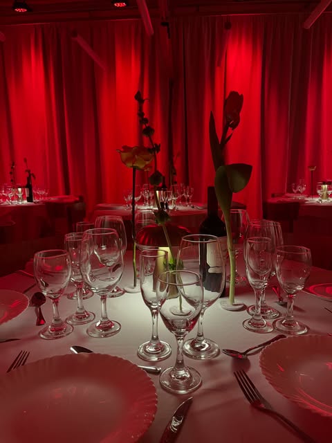 El salón montado para cena, con la luz roja del escenario.